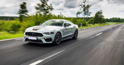 Gray Ford Mustang Mach 1 equipped with Öhlins suspension speeding down a countryside road.