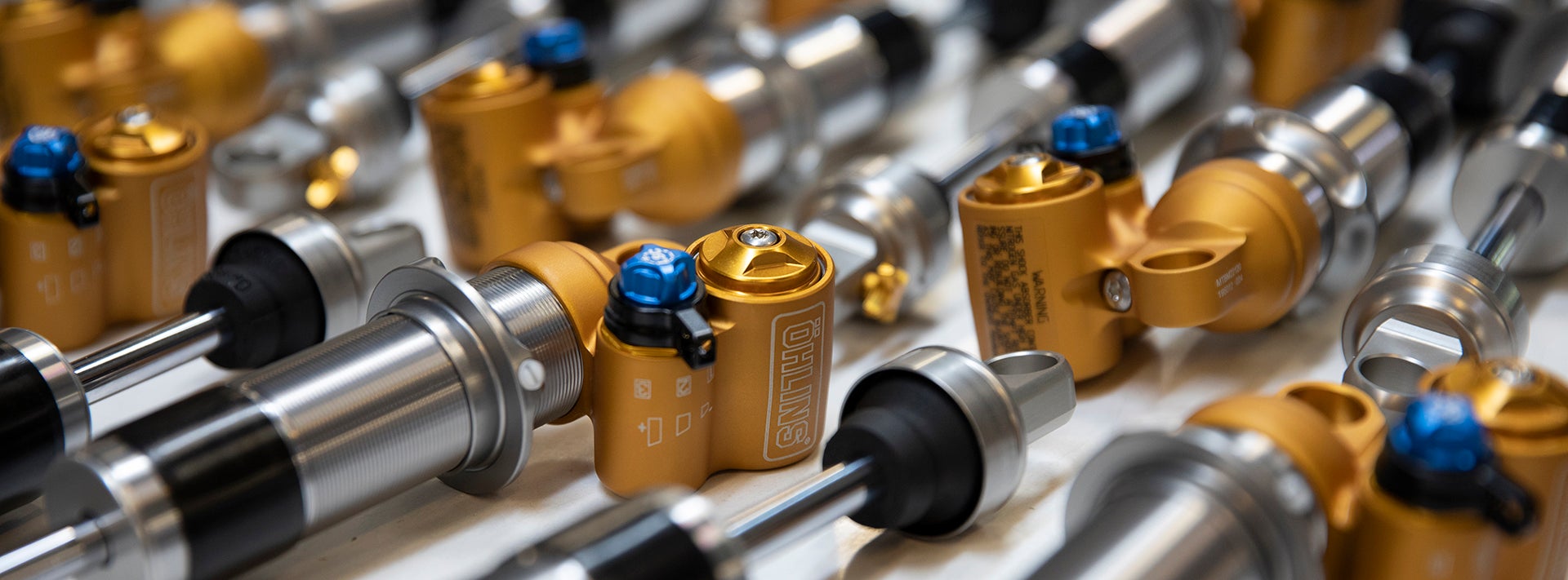 Multiple Öhlins suspension components on an assembly table in the factory.